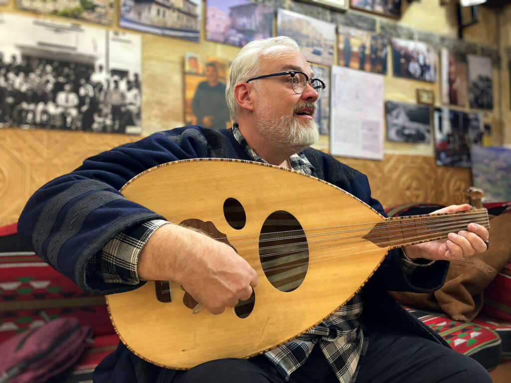 Brian J. Bowe plays the oud, a traditional Arabic instrument, at a community hub in Irbid, Jordan, at Yarmouk University in fall 2024. 