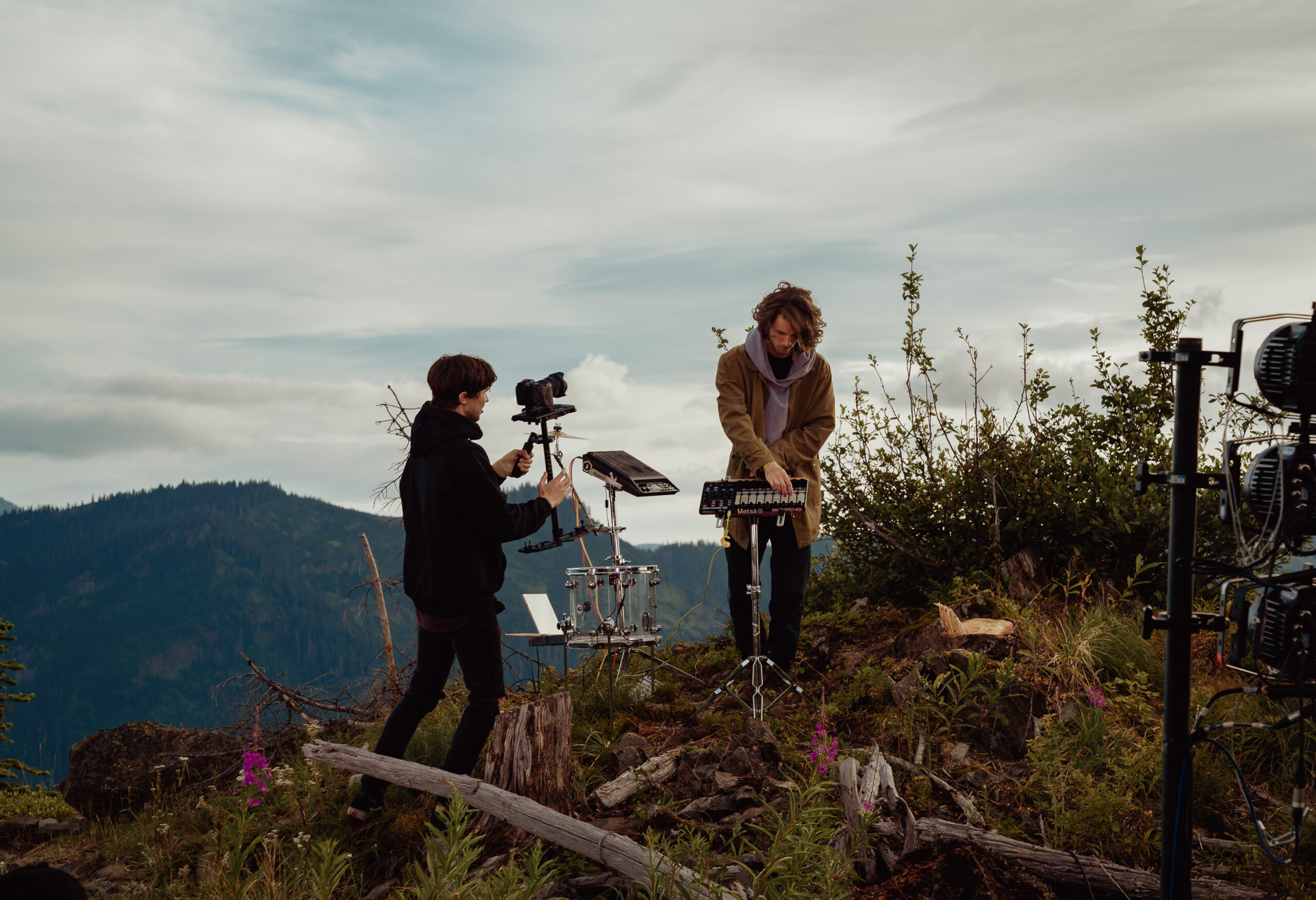 Connor Jalbert films a musician playing on a grassy hill on the set of a video shoot for "In the Cascades."