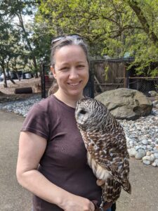 Colleen van Pelt stands outside with an owl on her arm.