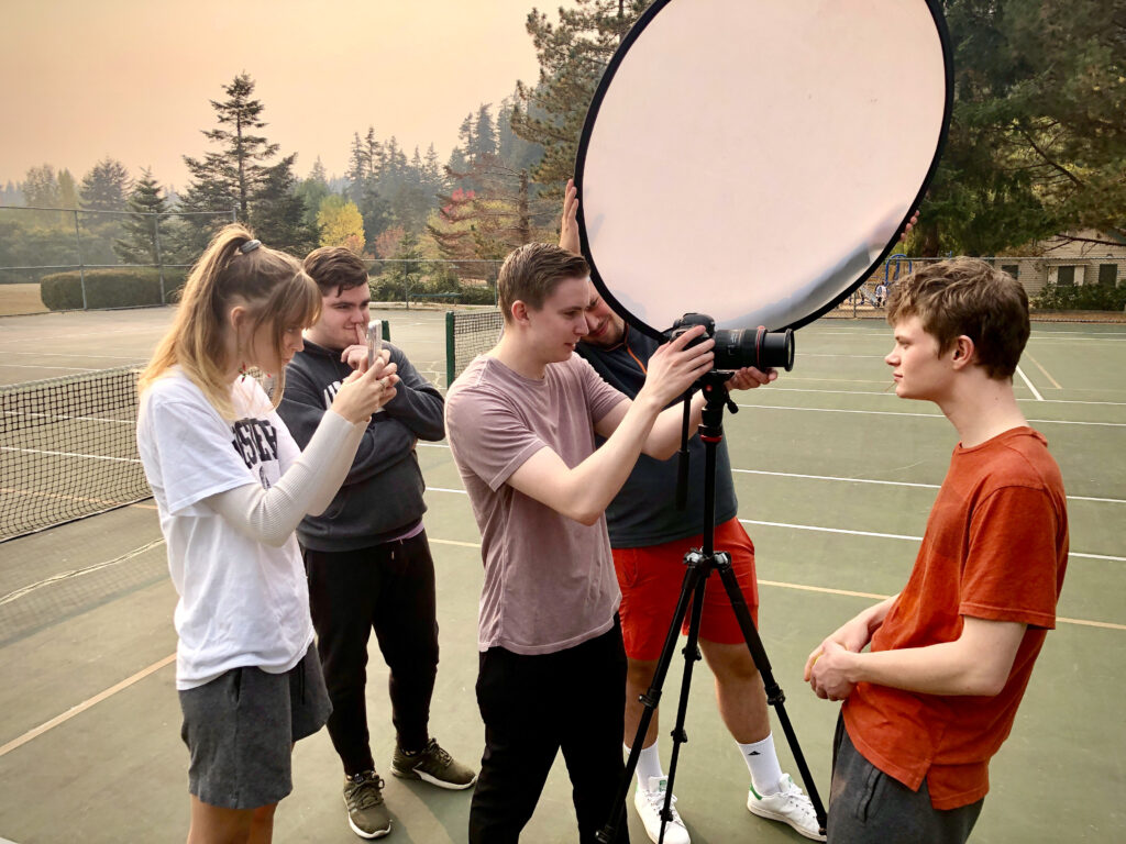 Five college students on a pickleball court take turns photographing each other.