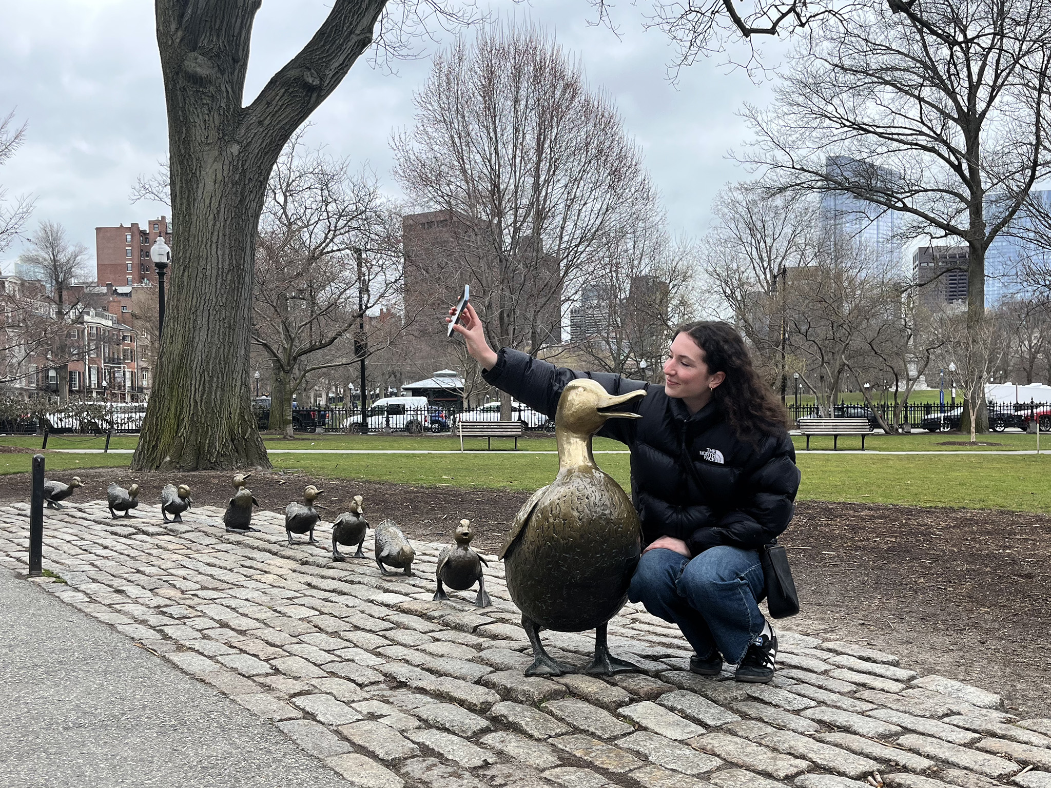 A woman takes a selfie next to the "Make Way for Duckling" statues in Public Garden in Boston 