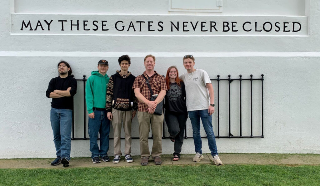 Canadian-American Media Systems class taught by Derek Moscato pose in front of the Peace Arch monument. 